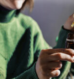 Close-up de uma mulher segurando um frasco de óleo de CBD e um conta-gotas, simbolizando o uso de canabinoides como uma opção de tratamento para depressão.