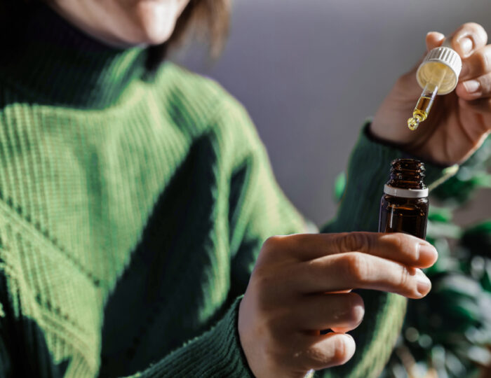 woman-holding-a-dropper-of-sublingual-cbd-cannabis-2025-02-13-01-03-16-utc Close-up de uma mulher segurando um frasco de óleo de CBD e um conta-gotas, simbolizando o uso de canabinoides como uma opção de tratamento para depressão.