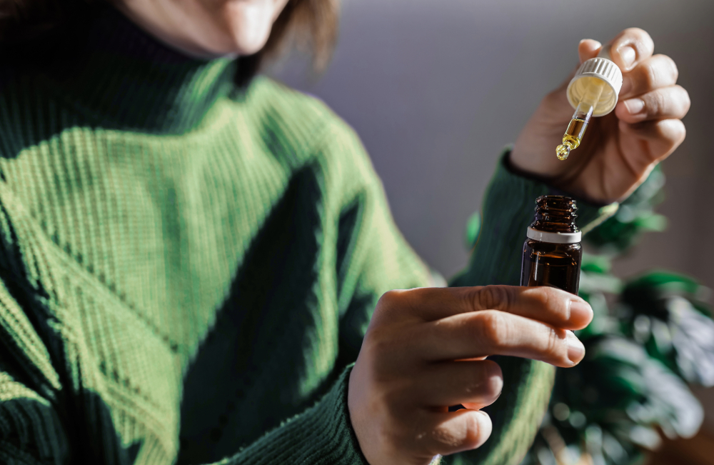 Close-up de uma mulher segurando um frasco de óleo de CBD e um conta-gotas, simbolizando o uso de canabinoides como uma opção de tratamento para depressão.