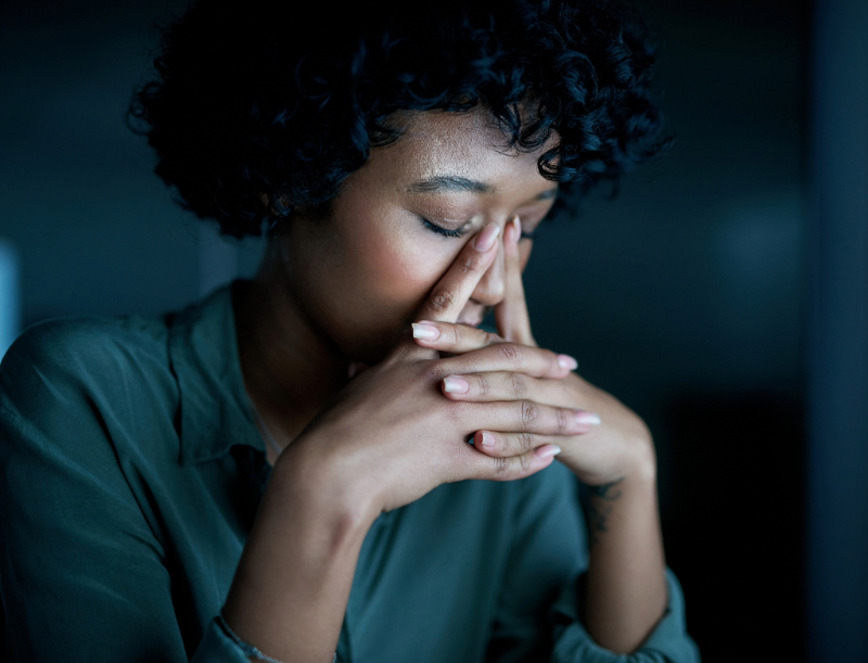 Uma mulher com expressão de preocupação e cansaço, com os olhos fechados e a mão no rosto, representando o peso e o estado interno da depressão.